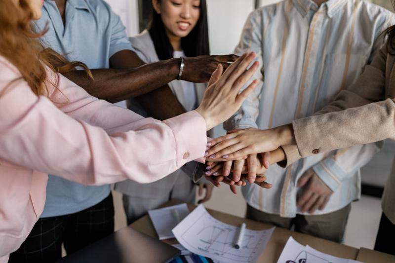 Une équipe réunit ses mains au-dessus d'une table de travail