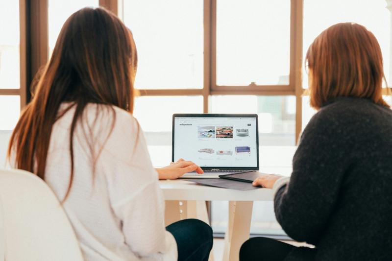 Deux personnes consultent un site internet sur un ordinateur portable